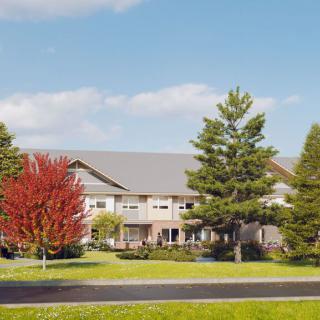 A view of a building surrounded by trees and a well-maintained lawn under a clear blue sky.
