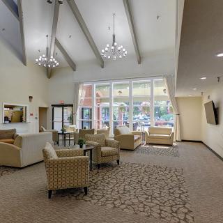 A modern lobby area featuring comfortable seating, large windows, and elegant chandeliers.