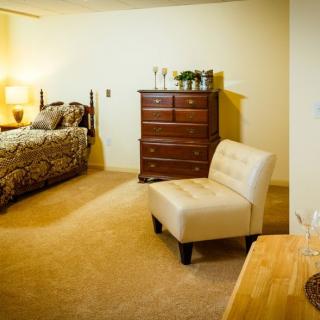 A cozy bedroom with a bed, dresser, and a comfortable chair.