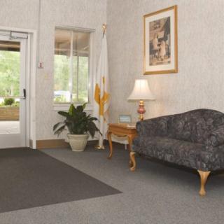 A cozy lobby area with a sofa, lamp, plant, and artwork near an entrance.