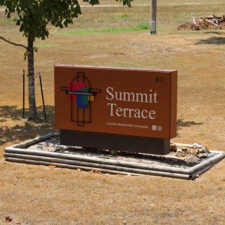 A sign for Summit Terrace stands amidst a landscaped area.