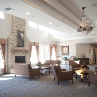 A spacious and elegantly decorated living room with a fireplace, multiple seating areas, and large windows providing natural light.
