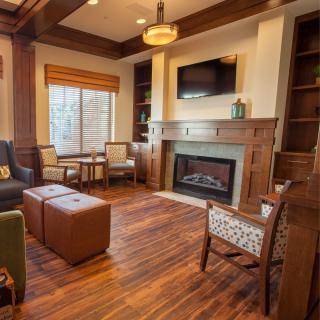 A cozy living room with a wooden floor, featuring a fireplace, seating area, and television.