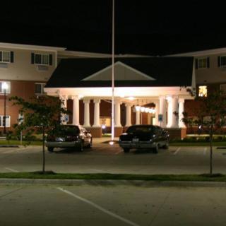 A well-lit building at night with cars parked in front.