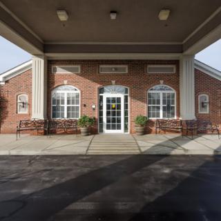 Entrance of a brick building with large windows and benches.