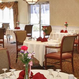 An elegant dining room with tables set for a meal, decorated with flowers and napkins.