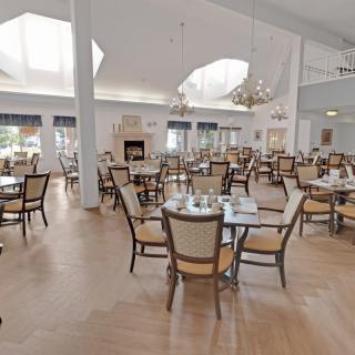A spacious dining area with tables and chairs, illuminated by chandeliers.
