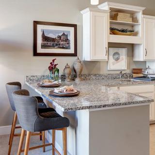 A modern kitchen interior featuring a granite countertop with bar stools and stylish decor.
