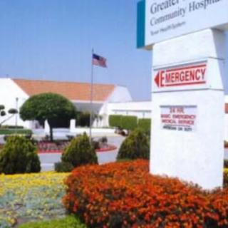 A hospital with an emergency entrance sign surrounded by a landscaped garden.