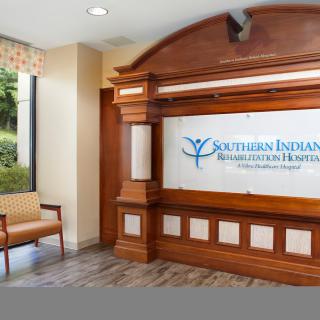 The reception area of a hospital lobby featuring wooden accents and a sign for Southern Indiana Rehab Hospital.