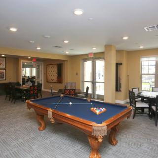A recreation room featuring a pool table and seating areas.
