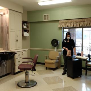A stylist standing in a hair salon, equipped with a salon chair and other hairstyling tools.