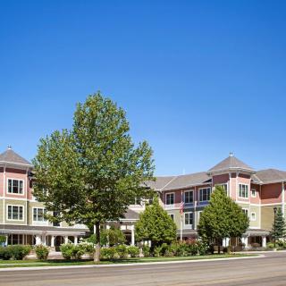 A modern building with a tree-lined facade under a clear blue sky.