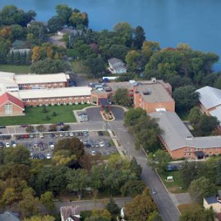 An aerial view of a school campus surrounded by lush greenery and a serene lake.
