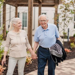 An elderly couple enjoying a walk together in the park.