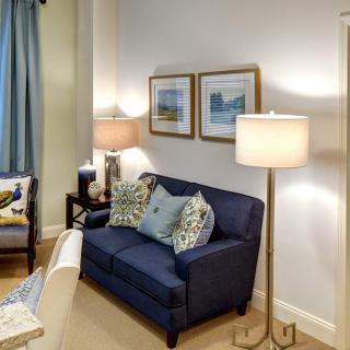 A cozy living room with a dark blue sofa, decorative pillows, and elegant lighting.