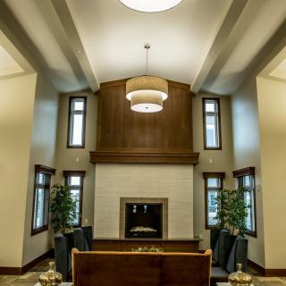 A modern living room with a high ceiling, featuring a central fireplace and contemporary decor.