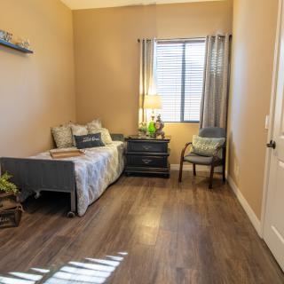 A cozy bedroom with a single bed, nightstand, and a chair by the window.