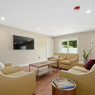A modern living room with a comfortable seating area, featuring a large television and stylish furniture.