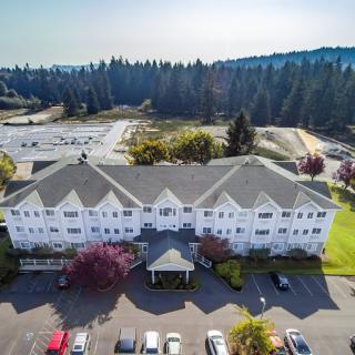 Aerial view of a large residential building with a parking lot surrounded by trees.