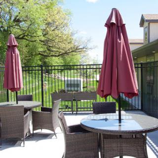A cozy outdoor patio setup with tables and umbrellas, surrounded by lush greenery.