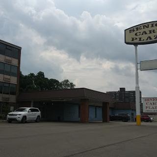 A photo of a commercial building featuring a prominent sign and an empty parking lot under a cloudy sky.