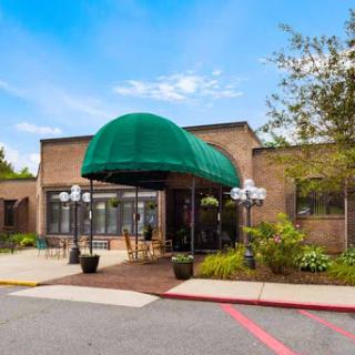 A welcoming entrance featuring a green awning and nicely landscaped surroundings.