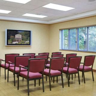 A conference room with rows of chairs facing a television.