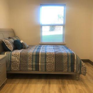 A cozy bedroom with a neatly made bed and a window letting in natural light.