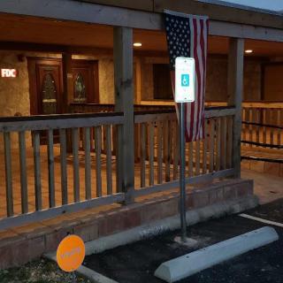 An evening view of a building with a porch featuring an American flag and an accessible parking sign.