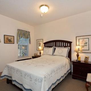 A cozy bedroom with a wooden bed frame, matching bedside tables, lamps, and decorative artwork on the walls.