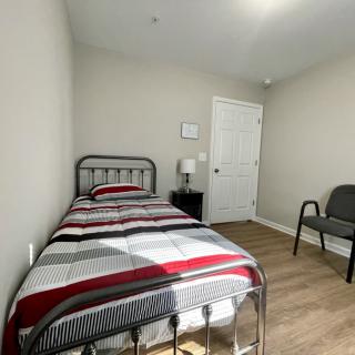 A minimalist bedroom with a single bed, chair, and nightstand.
