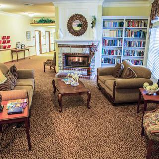 A cozy living room with sofas, a fireplace, and a well-stocked bookshelf.