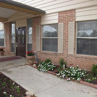 A welcoming entrance with blooming flowers and a brick facade.