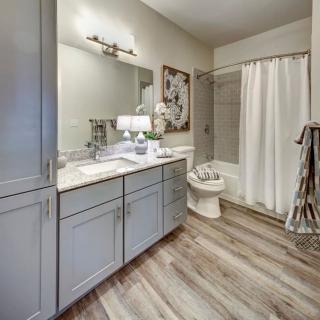 A modern bathroom with sleek cabinetry, a large mirror, and a shower curtain.