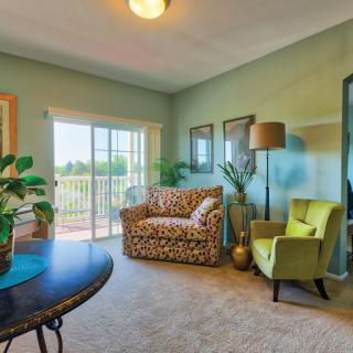 A cozy living room with colorful furniture and natural lighting from a large window.
