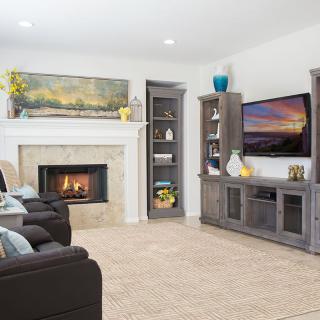 A cozy living room with a fireplace and TV, surrounded by comfortable seating and decorative shelves.