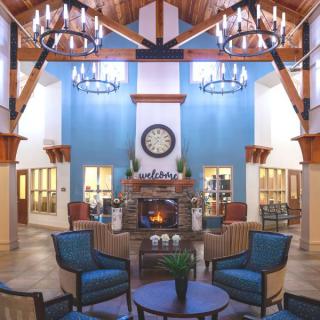 A cozy lobby interior with chandeliers and a fireplace surrounded by a comfortable seating area.
