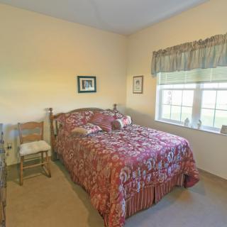 A cozy bedroom with a patterned bedspread and natural light coming through the window.