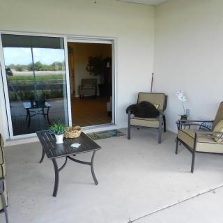 A cozy patio area with outdoor seating and a table, connected to the indoors by a sliding door.