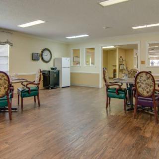 A spacious dining area with elegant chairs and tables, featuring a wooden floor and a refrigerator in the corner.