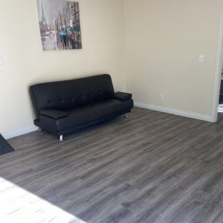 A minimalist living room with a black sofa and hardwood flooring.