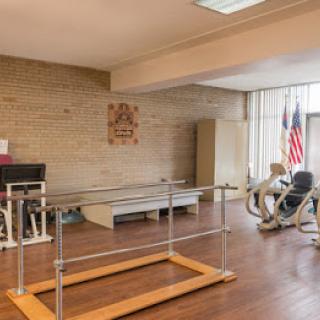 A well-equipped physical therapy room featuring parallel bars and exercise equipment.