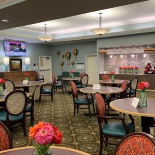 A well-decorated dining area with neatly arranged tables and chairs, adorned with fresh flowers and soft lighting.
