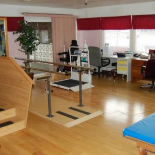 A rehabilitation therapy room equipped with parallel bars and exercise equipment.