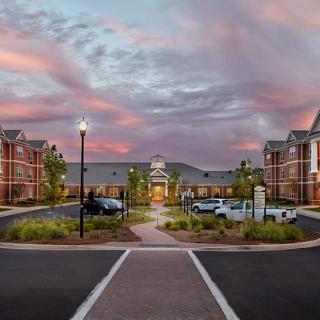 A modern building with a parking lot at sunset, featuring street lamps and a clear pathway.