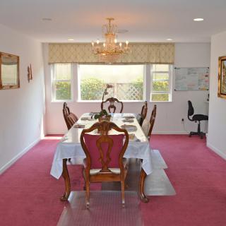 Elegant dining room with a chandelier, set table, and pink carpet.