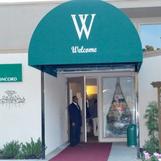Entrance to a building featuring a green awning with a welcome sign.