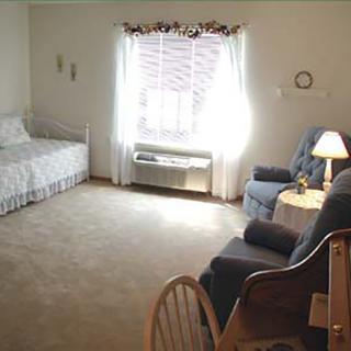 A cozy bedroom with a single bed, armchair, and a window with curtains.