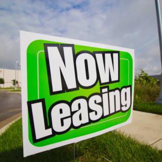 A sign displaying 'Now Leasing' indicating available property for rent.